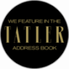 A black circular badge with gold text reading We feature in the Tatler Address Book. The word Tatler is in large, bold letters in the centre.